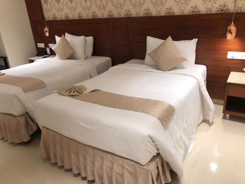 two beds in a hotel room with white sheets at Hotel the Plaza in Hyderabad