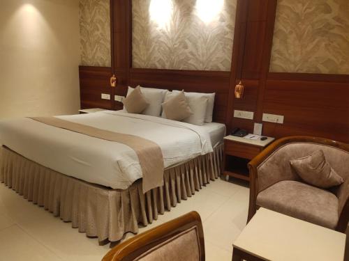 a bedroom with a large bed and a chair at Hotel the Plaza in Hyderabad