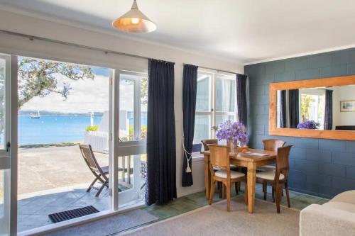 comedor con mesa y vistas al océano en The Nest Russell Waterfront Central Cottage, en Russell