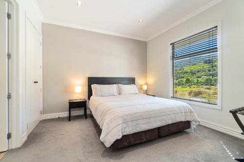 a white bedroom with a bed and a window at Valley Villa - Cardrona Holiday Home in Cardrona