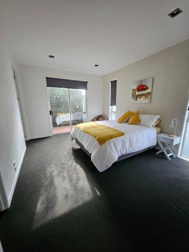 ein Schlafzimmer mit einem großen Bett und einem Fenster in der Unterkunft Golden Sands Beachside Cottage in Papamoa