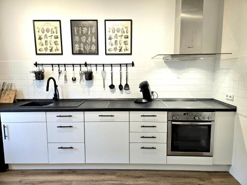 a kitchen with white cabinets and a sink at WieApart - Ruhig im Grünen, Parkplatz, zw. DUS/CGN in Leverkusen