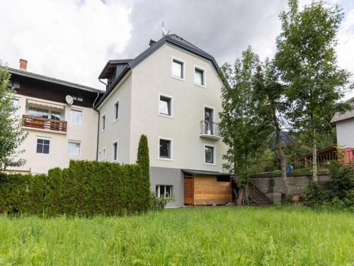 een wit huis met een houten deur in een tuin bij Gailtaler apartment at an excursion location in Kötschach
