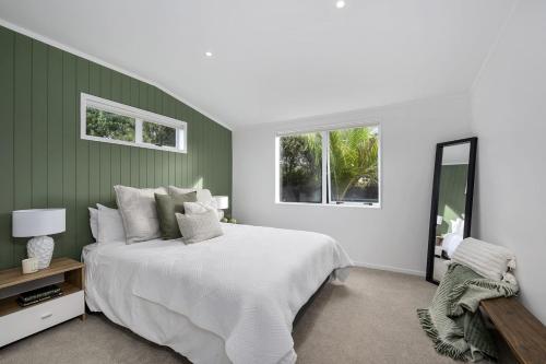1 dormitorio con 1 cama grande y 2 ventanas en The Love Shack - Matakana Holiday Home, en Warkworth