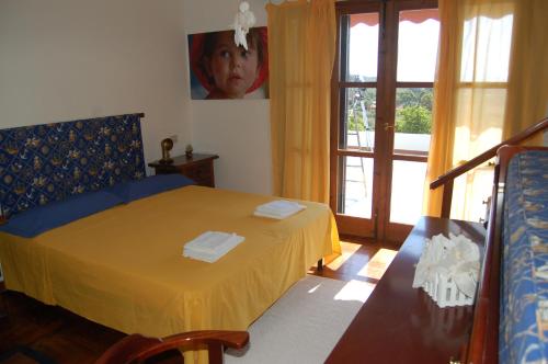 una camera da letto con un letto con lenzuola gialle e una finestra di Villa delle torri a Pula