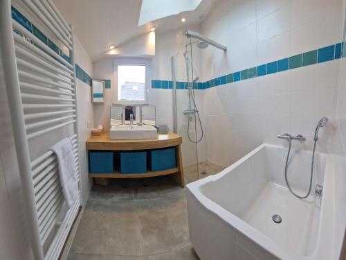 Baño blanco con bañera y lavamanos en Holiday home, flair&premium comfort near the beach, en Plougasnou