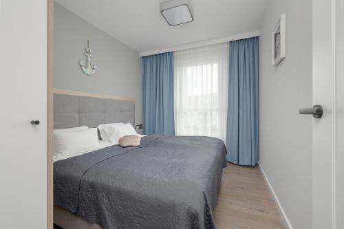 1 dormitorio con 1 cama y una ventana con cortinas azules en Perfect Holiday Apartments Bel Mare by Renters, en Międzyzdroje