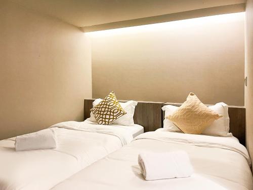 two beds in a room with white sheets and pillows at ST Signature Jalan Besar in Singapore