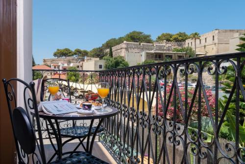 a balcony with a table with two glasses of orange juice at John & Mary Suites in Rethymno Town