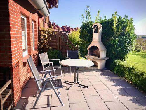 a patio with a table and chairs and a pizza oven at F4a EG - Fasanenblick in Petersdorf auf Fehmarn