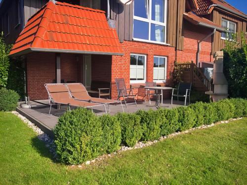 une terrasse avec des chaises et une table en face d'une maison dans l'établissement F4a EG - Fasanenblick, à Petersdorf auf Fehmarn