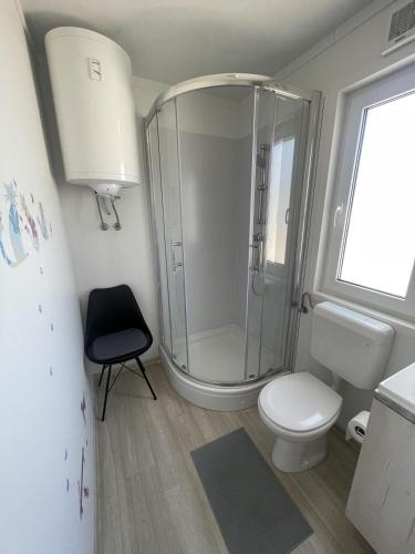 a bathroom with a shower and a toilet and a chair at Arabela Lux Villa in Pakoštane