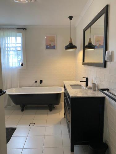 a bathroom with a tub and a sink and a mirror at GARRU FARM…. A perfect rustic farm stay near Orange in Orange