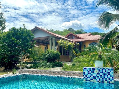 uma casa com piscina em frente a uma casa em Kapal Terbang Guest House Langkawi em Pantai Cenang