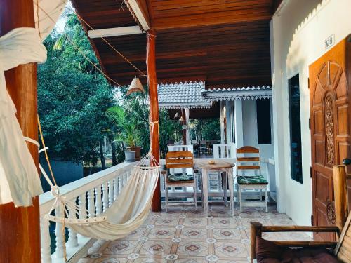 Ban Madua Wan的住宿－MY HOME Resort - Koh phangan vacation house rentals，门廊配有吊床和桌椅