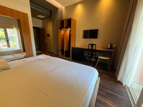Schlafzimmer mit einem Bett und einem Schreibtisch mit einem TV in der Unterkunft Olivia's Hill Resort in Durrës