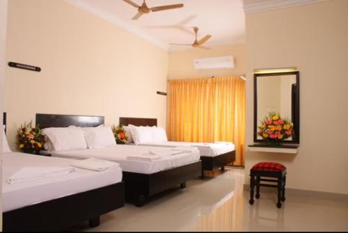a hotel room with two beds and a mirror at HOTEL BHARANI in Kanyakumari