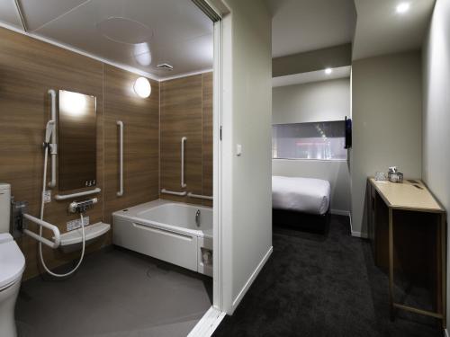 un letto e un bagno con vasca e servizi igienici. di Shinjuku Granbell Hotel a Tokyo