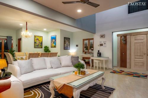 a living room with a white couch and a table at Ekostay Gold- Aqua Beach Villa I Partial Sea View I 1 min Walk to the Beach in Candolim