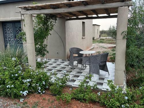 a patio with a table and chairs under a pergola at Dar Tiziri Amizmiz in Marrakech