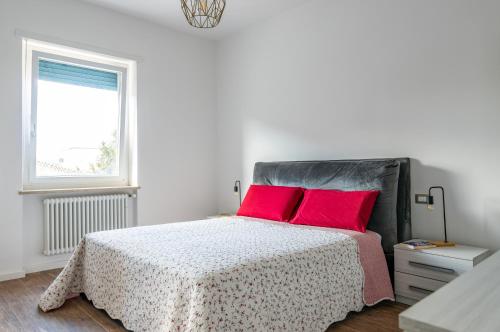 um quarto branco com uma cama com almofadas vermelhas em Verona - Sweety Apartment with Balcony! em Verona