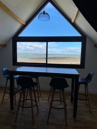- une table et deux chaises dans une chambre avec une grande fenêtre dans l'établissement Studio en résidence face à la mer -Sarzeau, à Sarzeau
