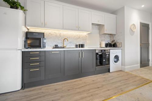 a kitchen with gray cabinets and a white refrigerator at WhiskAwayStays - Victoria House - Apartment 6 in Worcester