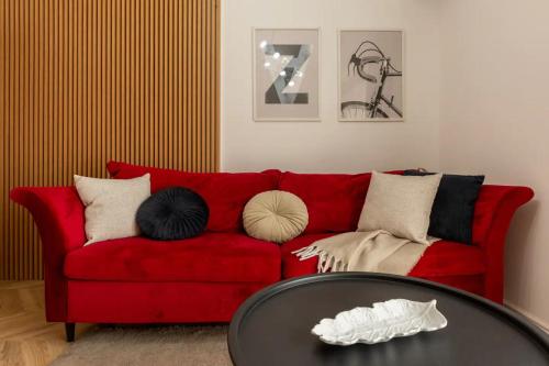 a red couch with pillows and a table in a living room at AIASTAY Bucharest River Apartments in Bucharest