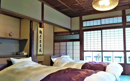Miwa的住宿－蔵の宿　櫻林亭，一间带两张床的卧室,位于带窗户的房间内