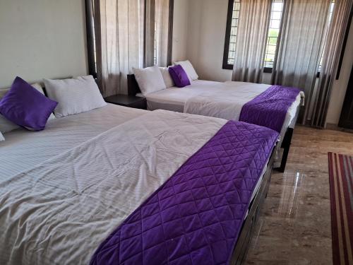 two beds in a room with purple sheets at Royal homes a4 in Kushālnagar