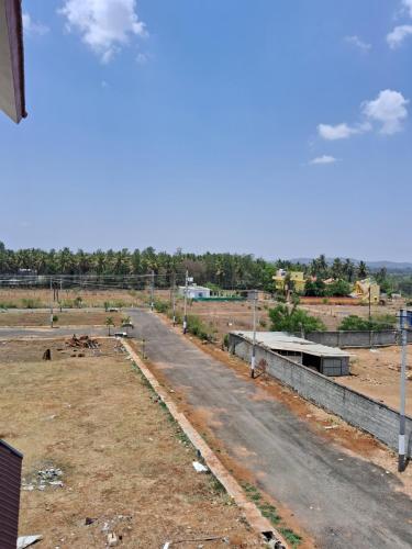 a dirt road in a field next to a street at Royal homes a4 in Kushālnagar