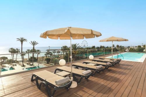 a deck with chairs and umbrellas and a swimming pool at Hotel Ocean House Costa del Sol, Affiliated by Meliá in Torremolinos