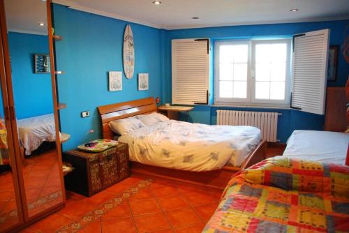 a bedroom with two beds and blue walls at Carmen - Habitación con vistas al mar in Santander