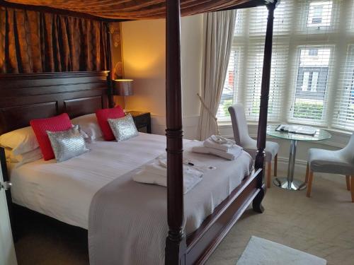 a bedroom with a four poster bed with red pillows at The Bath House Boutique B&B - IN-ROOM Breakfast - FREE parking in Bath