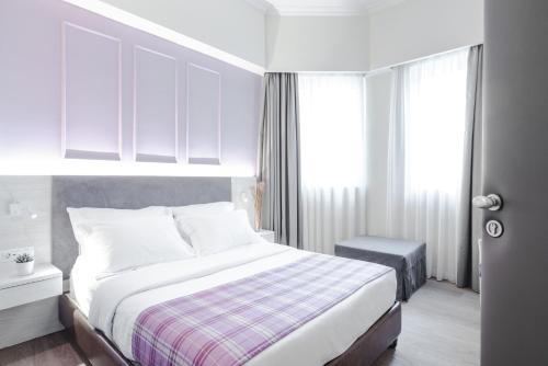 a white bedroom with a bed and a window at Athens Cypria Hotel in Athens
