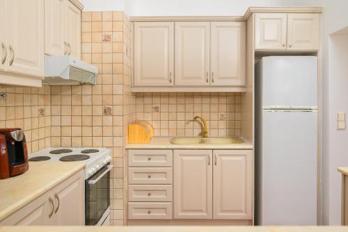 a kitchen with white cabinets and a sink and a refrigerator at Aris Studios in Hersonissos