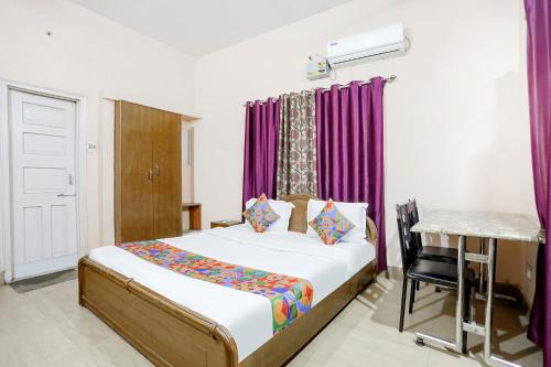 1 dormitorio con cama, mesa y cortinas moradas en FabExpress Corporate Stays, en Ranchi