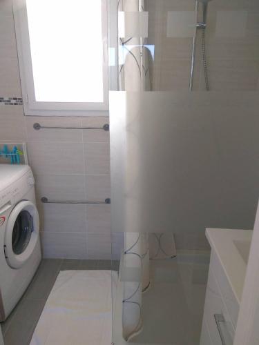 une salle de bains blanche avec un lave-linge et une fenêtre. dans l'établissement Gite Loire et Bois, à Saint-Martin-sur-Ocre