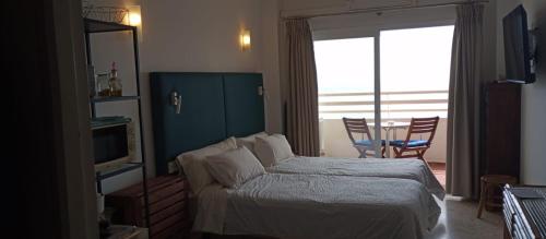 sypialnia z łóżkiem, telewizorem i oknem w obiekcie Seafront apartment with open-air heated pool w mieście Fuengirola