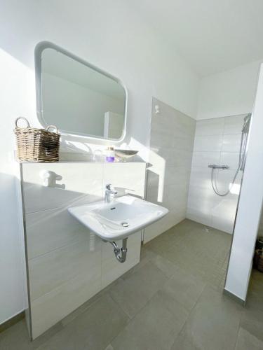 a white bathroom with a sink and a mirror at Ferienzimmer auf dem Hof Postma in Lambrechtshagen
