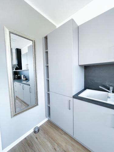 a white kitchen with a sink and a mirror at Ferienzimmer auf dem Hof Postma in Lambrechtshagen