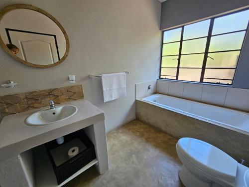 ein Badezimmer mit einem Waschbecken, einer Badewanne und einem Spiegel in der Unterkunft The Blyde Canyon House in Hoedspruit