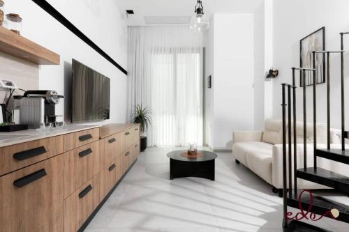 a white living room with a couch and a tv at דירת גן מפוארת על הים - By Edomlux in Eilat