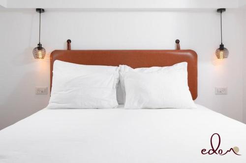 a bed with white pillows and two lights on it at דירת גן מפוארת על הים - By Edom in Eilat