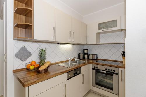 a kitchen with white cabinets and a wooden counter top at Appartementhaus Strandnähe in Warnemünde
