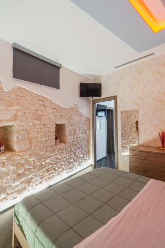 a bedroom with a stone wall and a bed at LUXUITE Spa con Piscina o Jacuzzi in Alberobello
