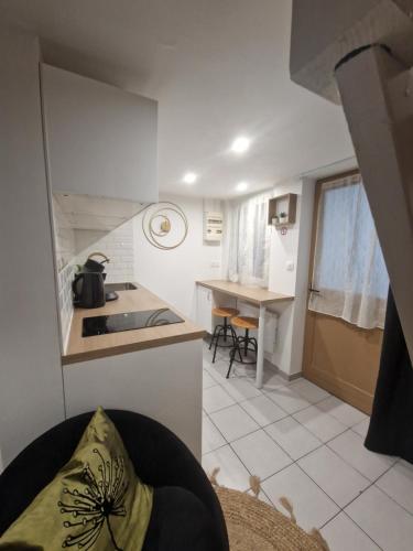 a small white kitchen with a counter and a table at LE PETIT TRIPLEX DES CARMELITES -COEUR HISTORIQUE in Rouen