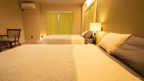 a hotel room with two beds and a chair at Hotel Re:Plug in Kochi