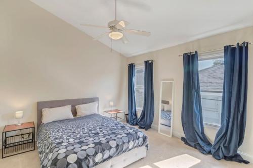 een slaapkamer met een bed met blauwe gordijnen en een plafondventilator bij Large 1 BR carriage house in historic SPR in Jacksonville