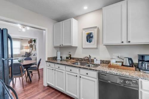 cocina con armarios blancos, fregadero y mesa en Modern 2 BR Condo - 2 block from San Marco en Jacksonville